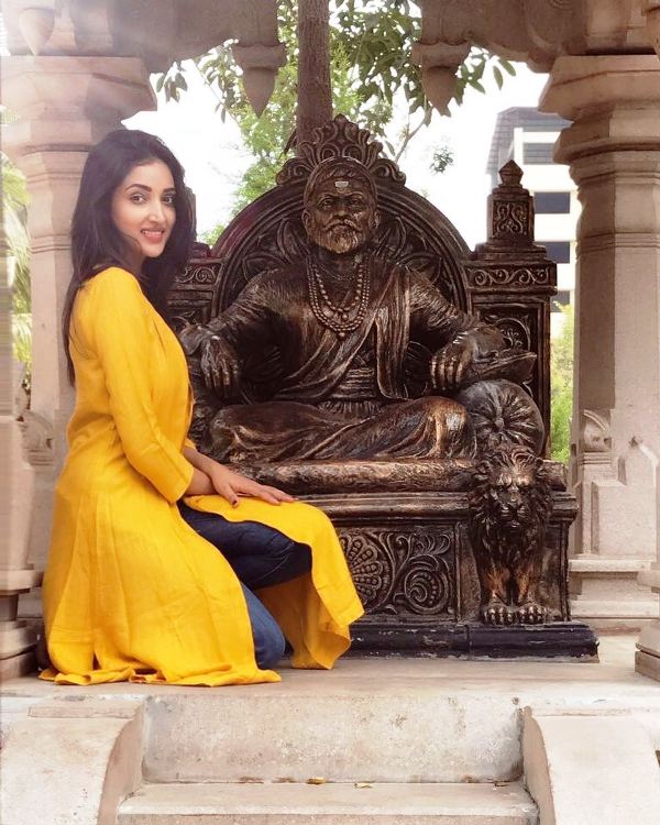 Rupali Bhosale Sitting In Front Of A Statue Of Shivaji