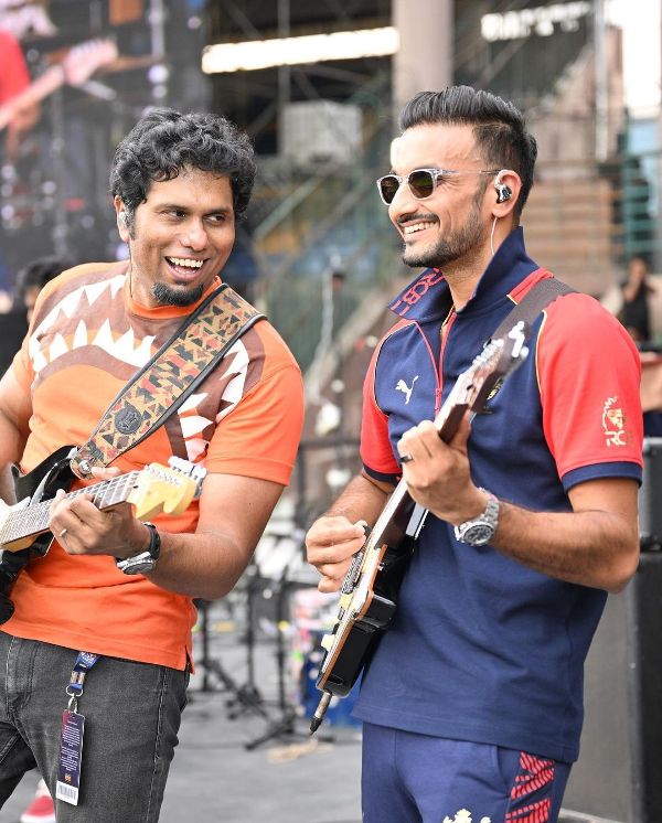 Harshal Patel (right) playing the guitar at an event