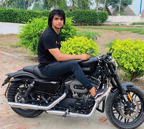 Neeraj Chopra posing on his motorcycle