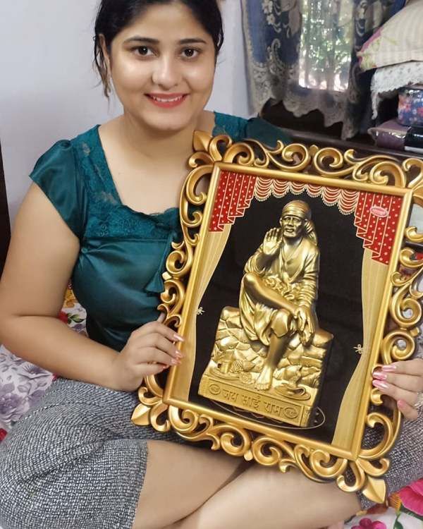 Neha Shree holding a picture frame of Shirdi Sai Baba