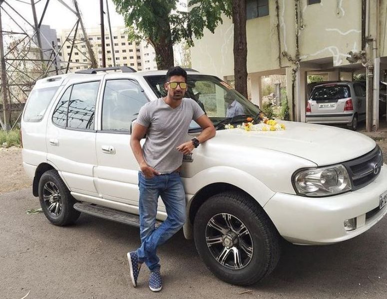 Akshay Waghmare posing with his Tata Safari car
