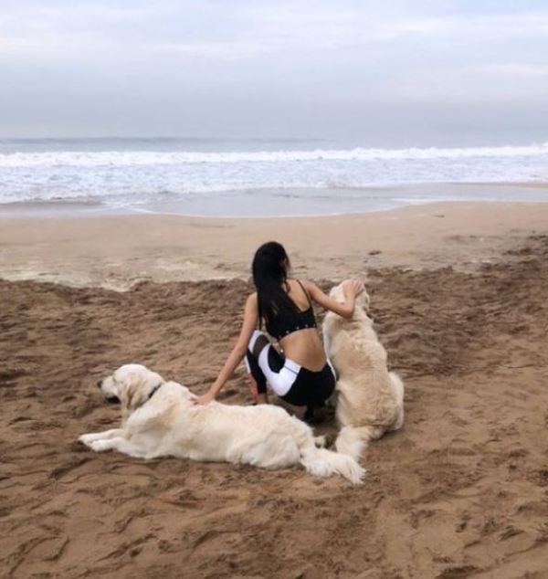 Andrea Kevichusa chilling on a beach with 2 dogs