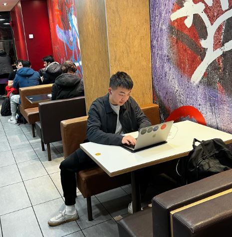 Carl Pei working on his laptop while sitting in a McDonalds outlet