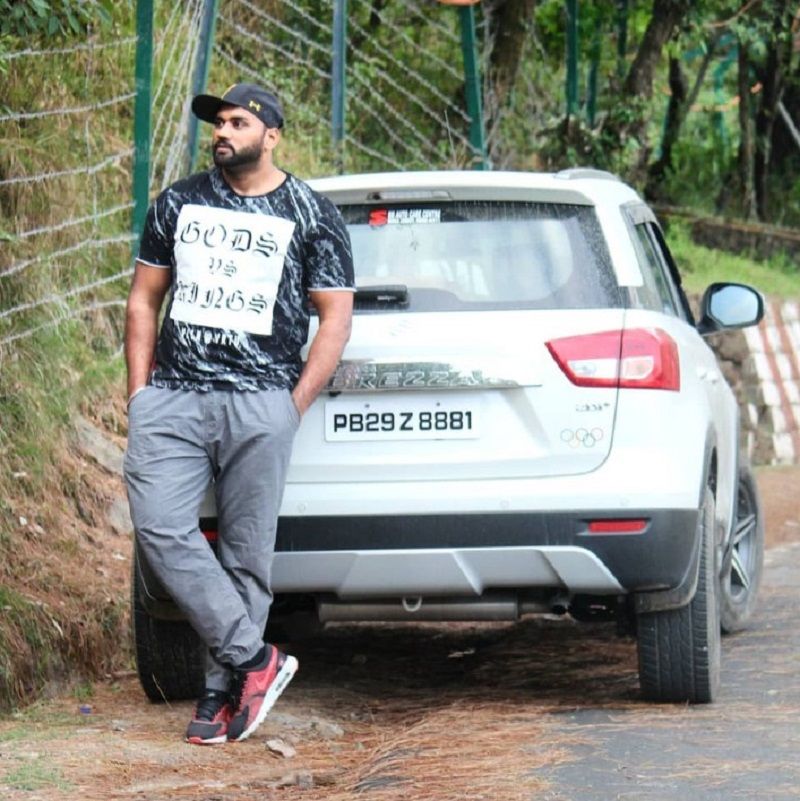 Tajinderpal Singh Toor posing with his Brezza car