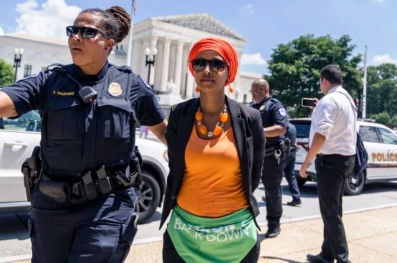 Ilhan Omar with a police personal after getting arrested