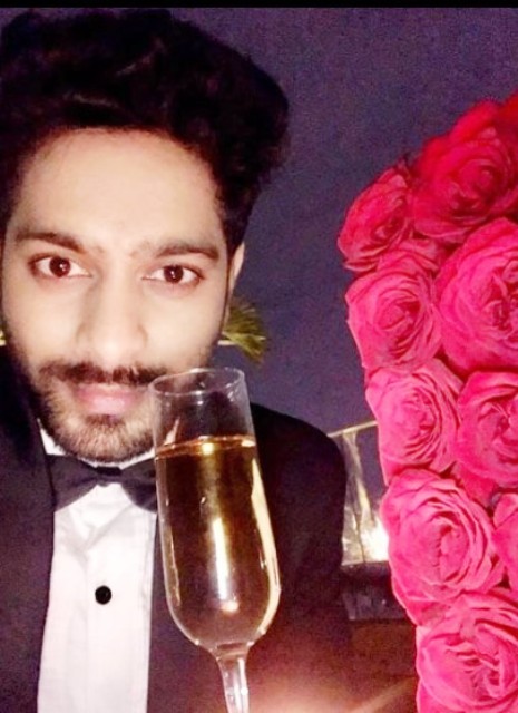 Raja Shekar posing for a photo with a glass of champagne in his hand