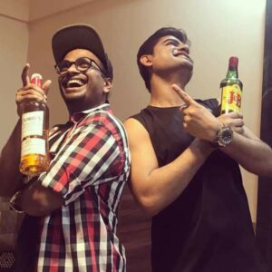 Srikant Maski (left) holding a bottle of alcohol