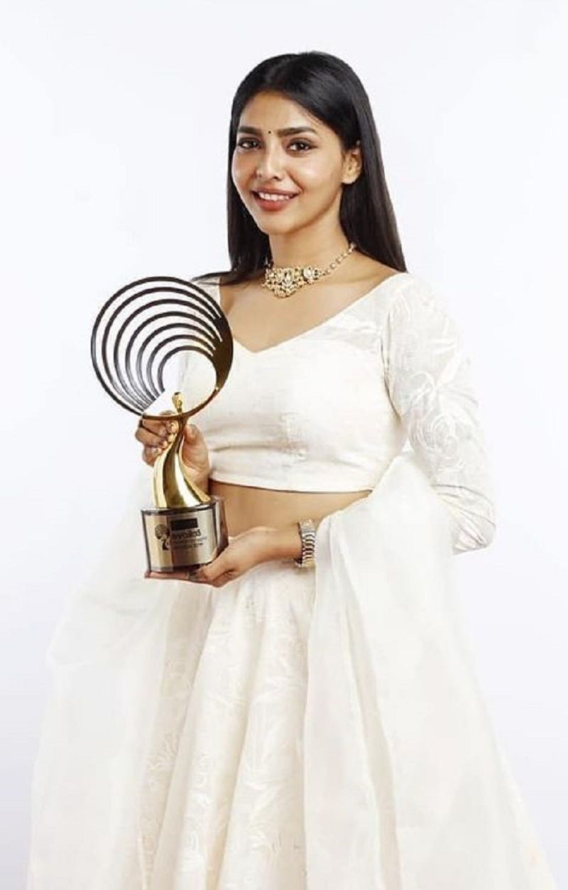 Aishwarya Lekshmi posing with best actress award for the film Vijay Superum Pournamiyum at Mazhavil Entertainment Awards