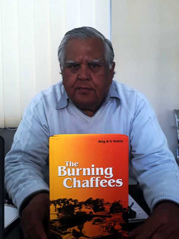A photo of Balram Singh Mehta holding his book The Burning Chaffees: A Soldier’s First-Hand Account of the 1971 War