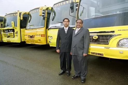Anand Sankeshwar and Vijay Sankeshwar standing for a photo in front of VLR Logistics Limited owned trucks