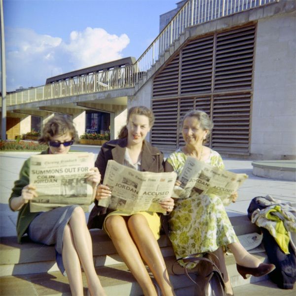 Savitri Devi with Diana Hughes (left) and Beryl Cheetham (middle) holding newspapers with headlines about Colin Jordan in the aftermath of the Cotswolds Camp in London, 1962