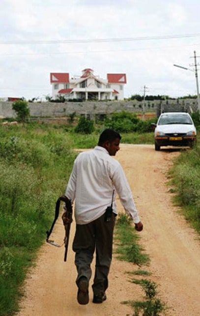 An armed guard patrolling the perimeter of Muthappa Rai's house