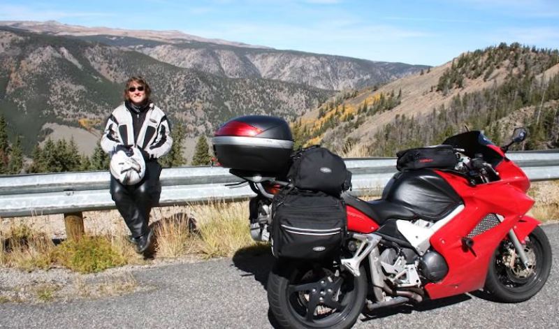 A picture of Christina Hammock Koch posing with her bike during her solo motorcycle trip across the US