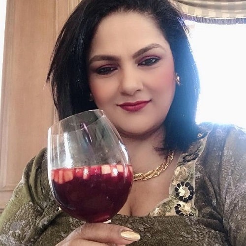 Guddi Maruti holding a glass of red wine