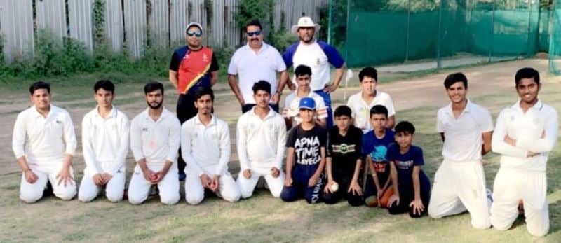 A photograph of Rajkumar Sharma with the students of the West Delhi Cricket Academy