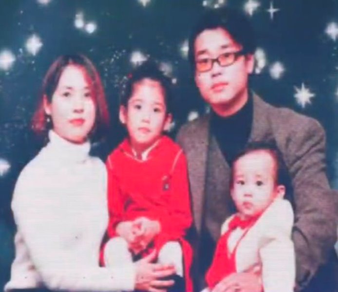 A childhood image of IU with her parents and brother
