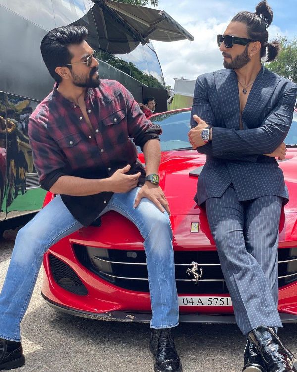 Ram Charan sitting on the bonet of his Ferrari with Ranveer Singh