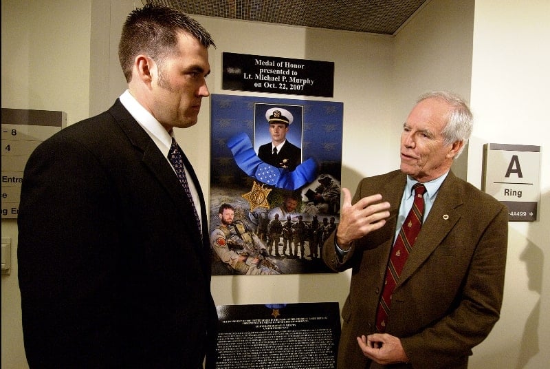 Michael P. Murphy's father with Navy SEAL Marcus Luttrell standing next to Michael's photo installed at the Hall of Heroes in Pentagon