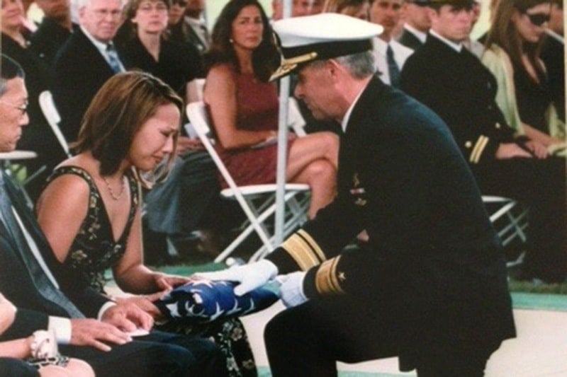 A US Navy SEAL officer presenting a folded American flag to Cindy during Matthew's funeral
