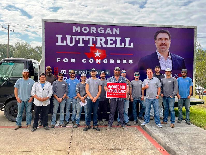 Texans standing infront of Morgan Luttrell's election board