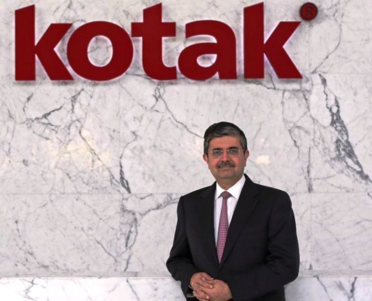 Uday Kotak posing for a photo under the logo of his company