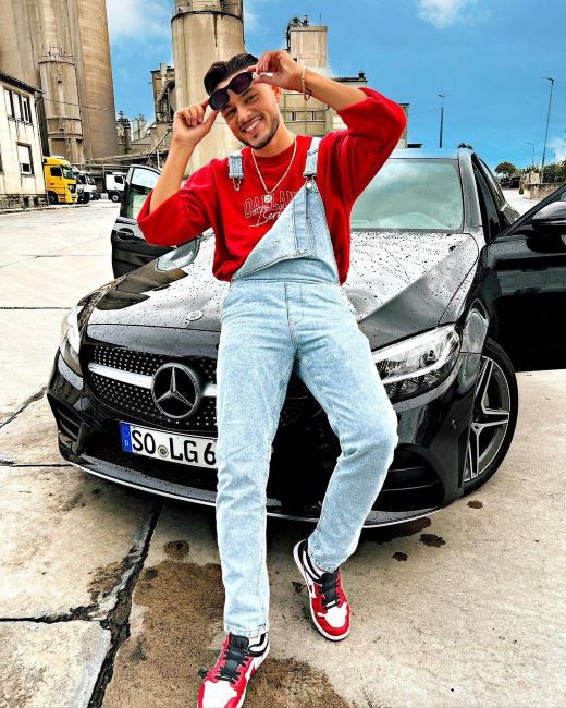 Leonardo Gashi sitting on the bonnet of his Mercedes-Benz car