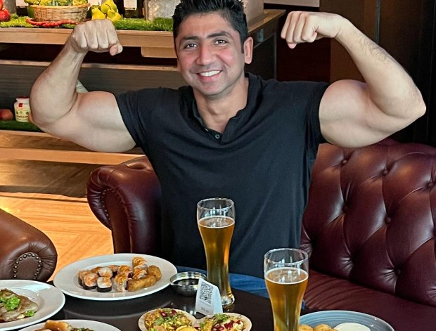 Mustafa Ahmed posing with the glasses of alcoholic beverages