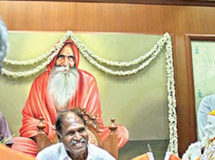 N. Rangaswamy sitting in front of the picture of Appa Paithiyam Swamigal