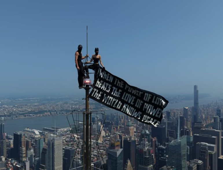 Angela Nikolau and Ivan Beerkus posing at the 1,454-foot antenna spire of the Empire State Building in New York City